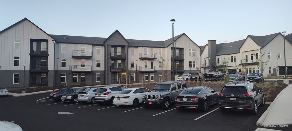 a parking lot full of cars in front of an apartment building