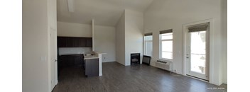 an empty living room with a kitchen in the background