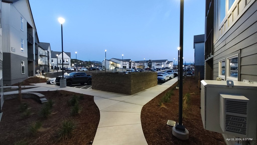 a view of a city street at night with buildings and a parking lot