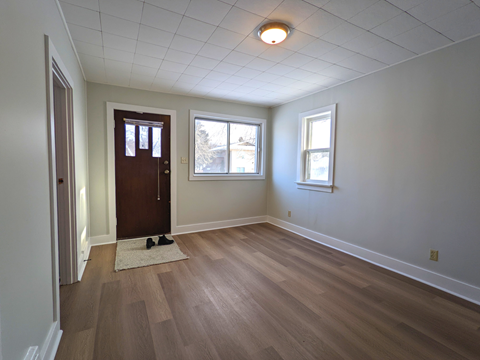 an empty living room with wooden floors and white walls