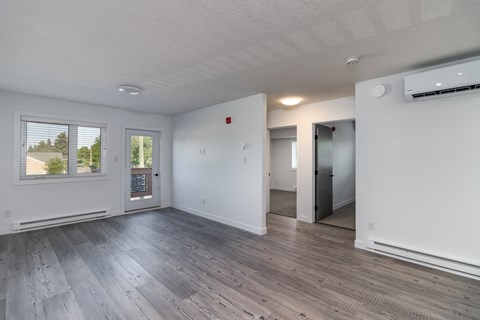the living room of an apartment with white walls and wood floors