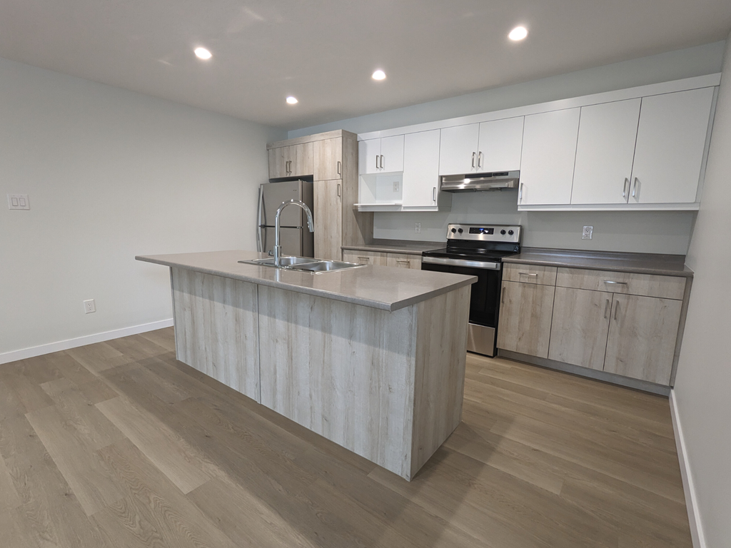 a kitchen with white cabinets and a large island with a sink