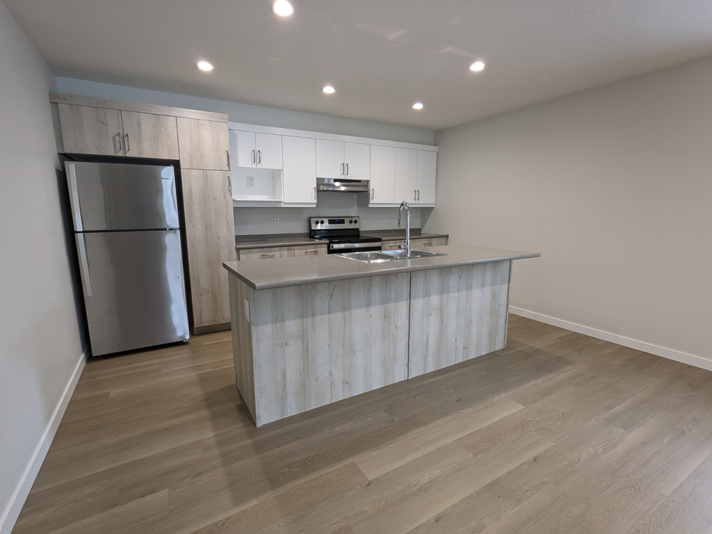 a kitchen with a large island and a stainless steel refrigerator