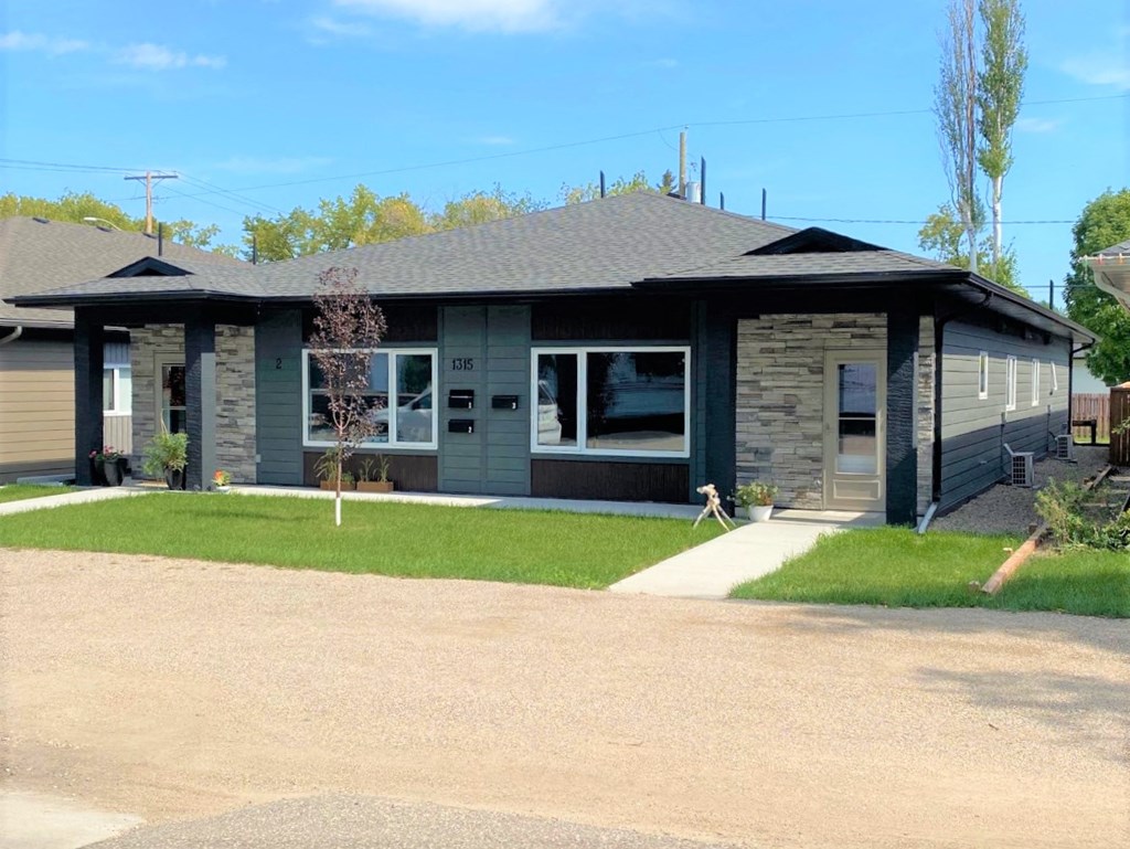 the front of a house with a driveway and lawn