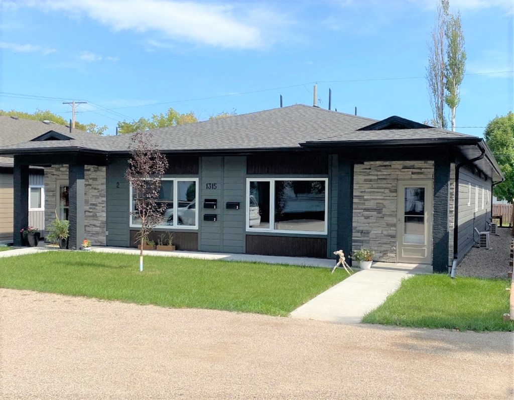 a gray and green house with a lawn and a sidewalk
