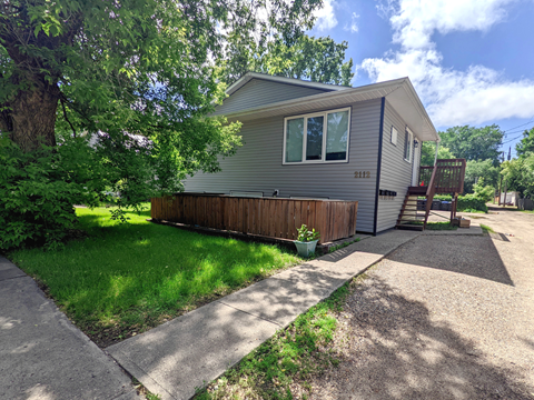a home with a wooden fence and a sidewalk in front of it