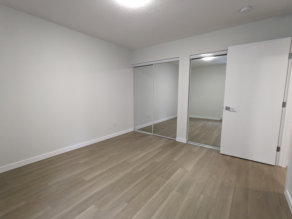 a bedroom with wood flooring and white walls and doors