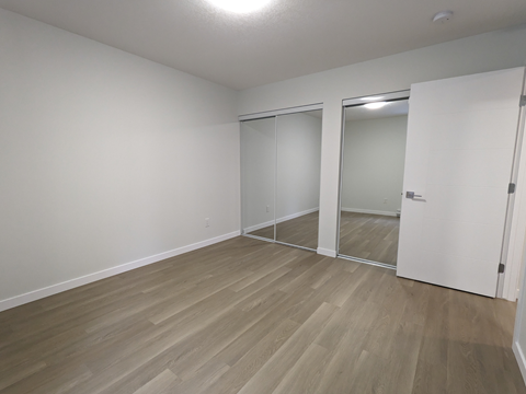 a bedroom with wood flooring and white walls and doors