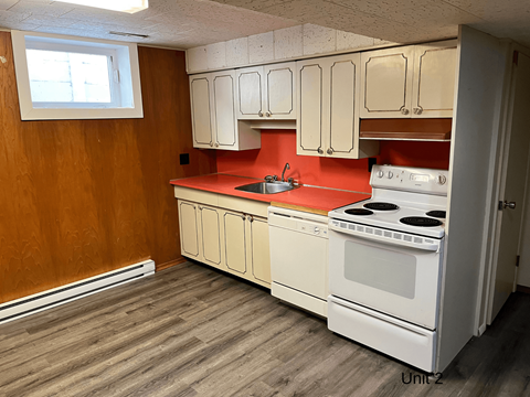 an empty kitchen with white appliances and red counter tops