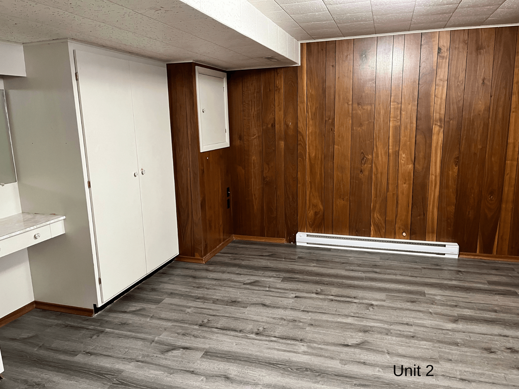 an empty room with wood flooring and white walls