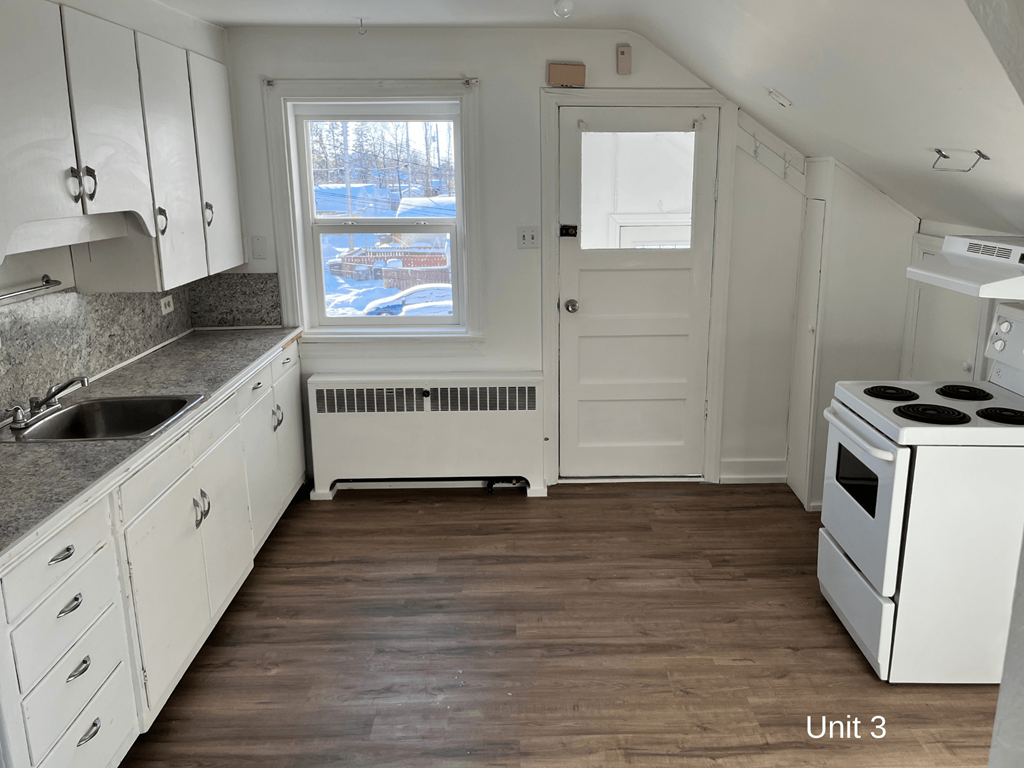 an empty kitchen with white appliances and white cabinets