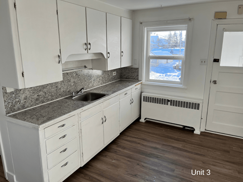 a kitchen with white cabinets and a sink and a window