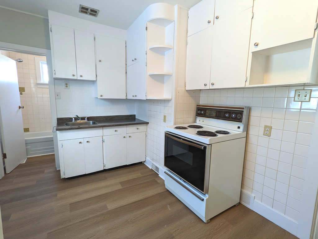an empty kitchen with white cabinets and a stove