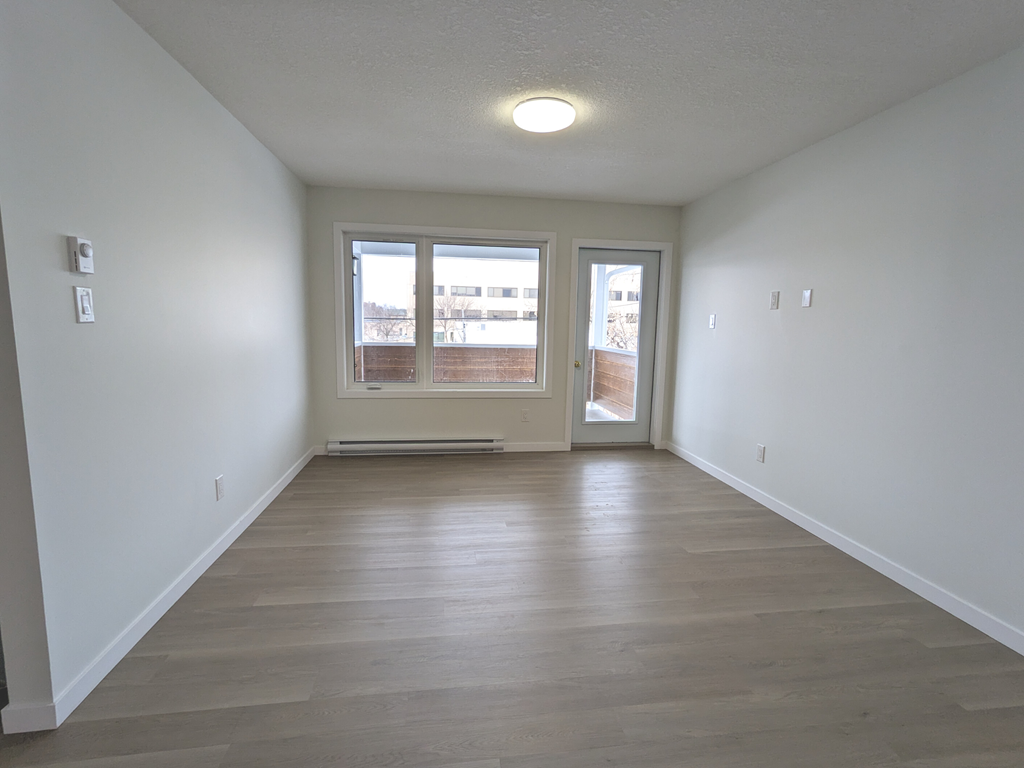 an empty living room with white walls and a window