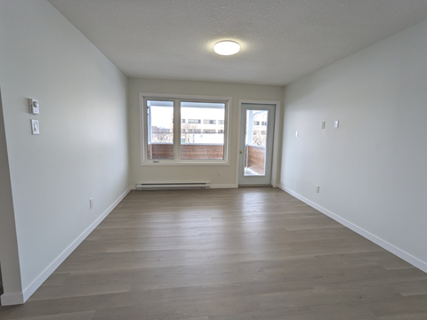 an empty living room with white walls and a window