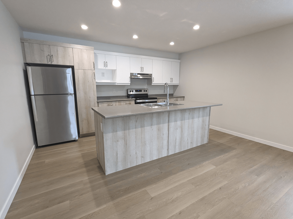 a kitchen with a large island and a stainless steel refrigerator