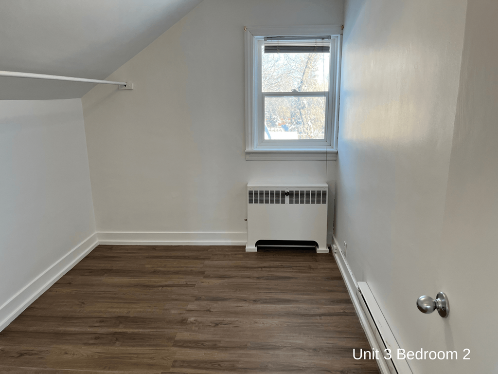 the upstairs room of a house with white walls and a window