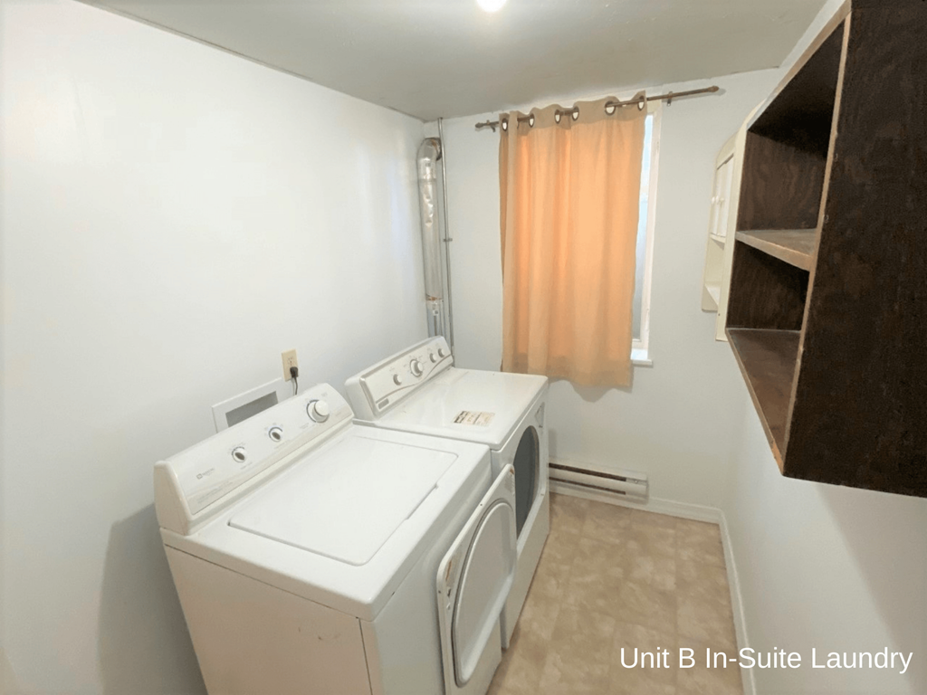 a laundry room with a washer and dryer and a window with a curtain