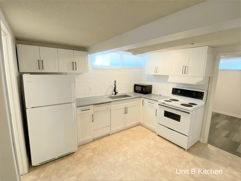 an empty kitchen with white appliances and white cabinets