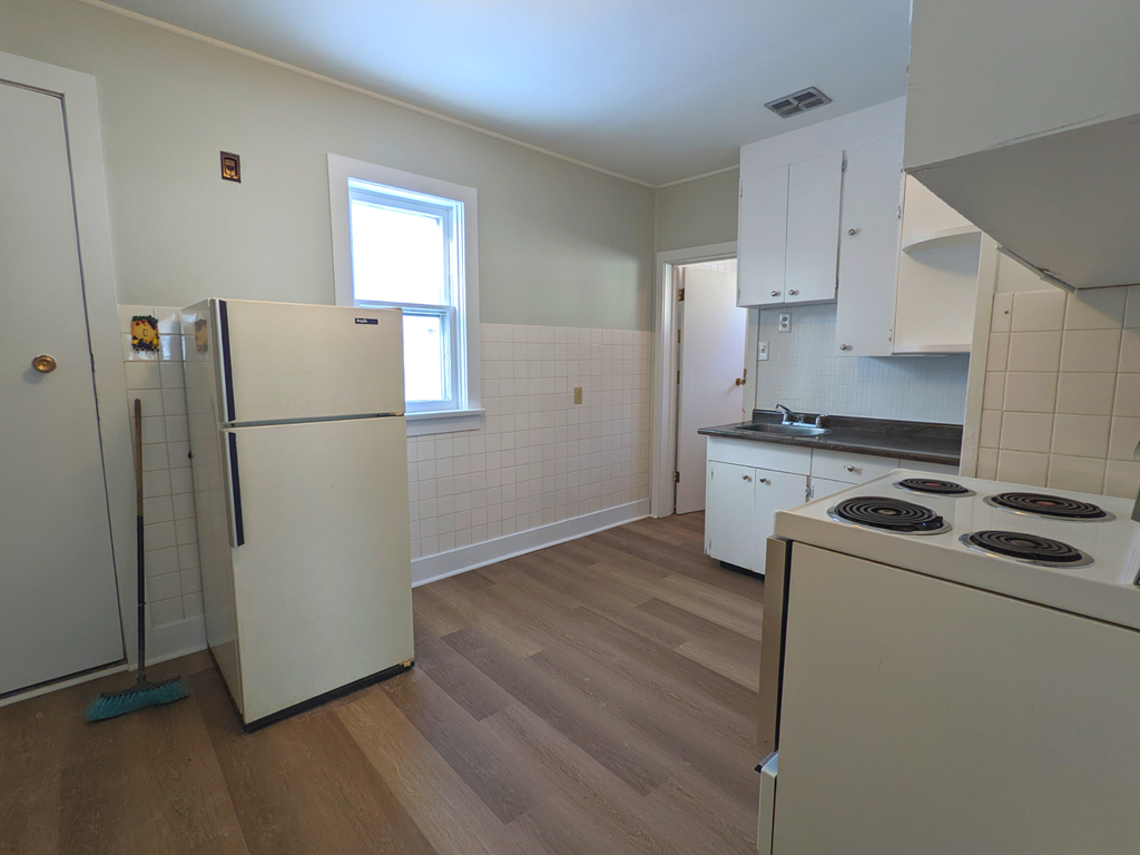 an empty kitchen with white appliances and a window