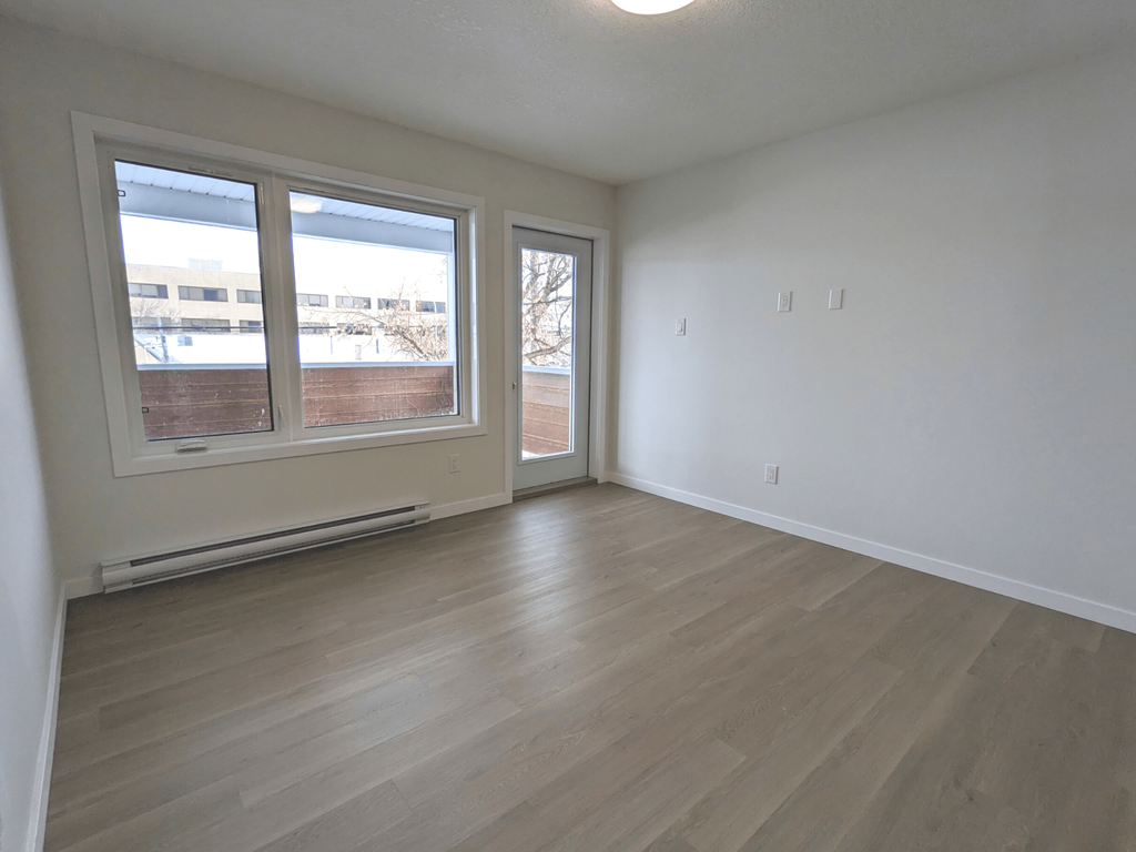 an empty living room with wood flooring and large windows