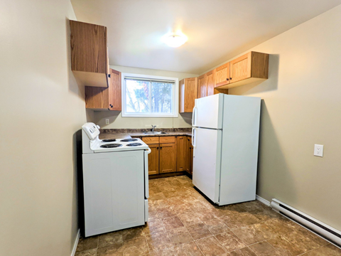 an empty kitchen with white appliances and wooden cabinets
