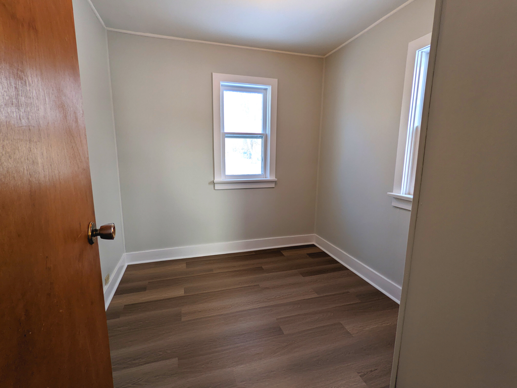 an empty room with wooden floors and a window