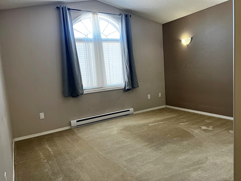 an empty living room with a window and a carpeted floor