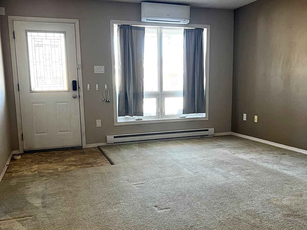 a room with a carpeted floor and a window with curtains