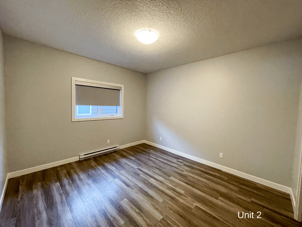the bedroom with hardwood flooring and a window