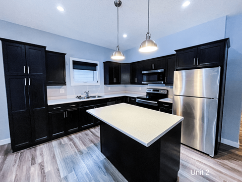 a kitchen with black cabinets and a stainless steel refrigerator