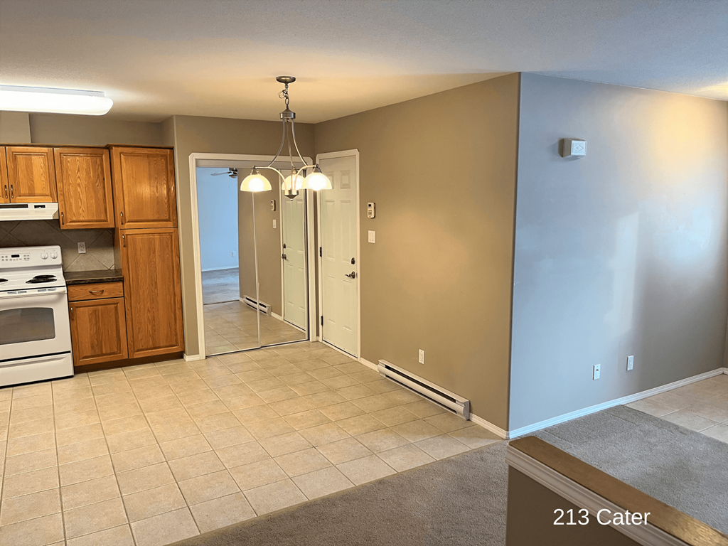 an empty kitchen and living room with a door into a hallway