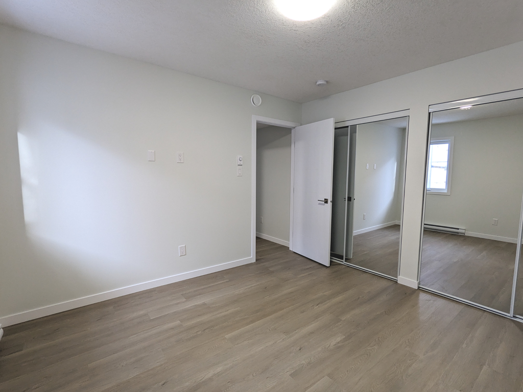 an empty living room with wood flooring and mirrors