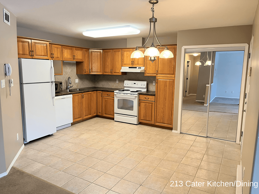 an empty kitchen with white appliances and wooden cabinets