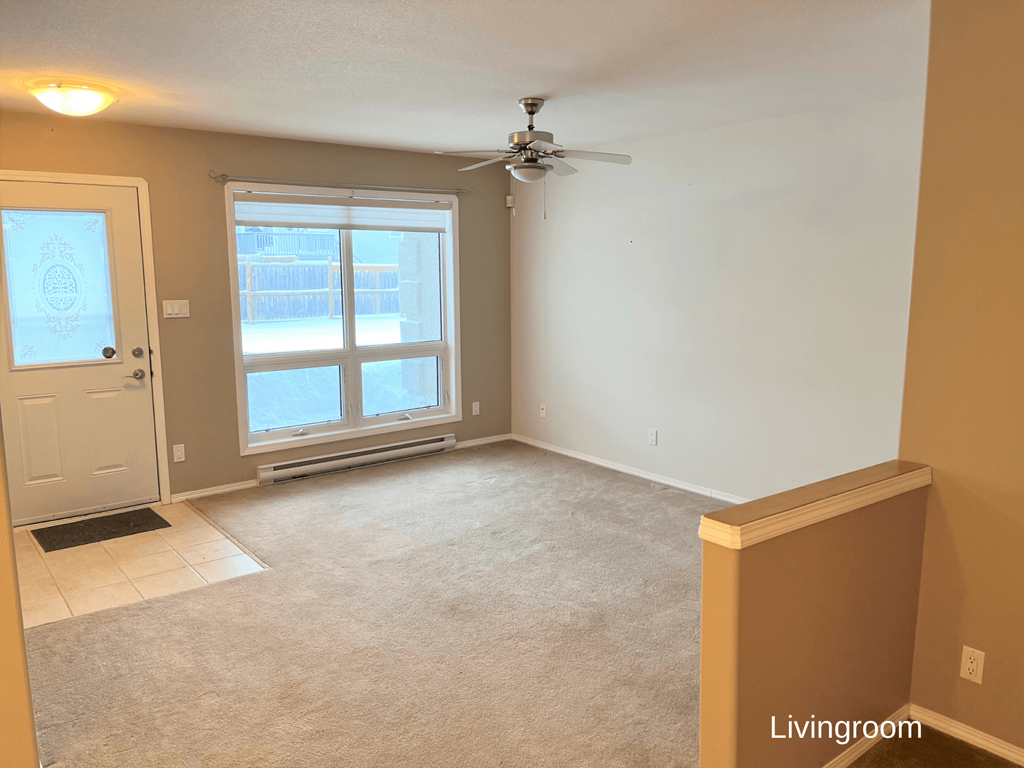 an empty living room with a ceiling fan and a window