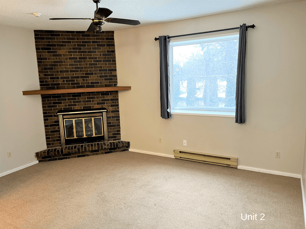 an empty living room with a fireplace and a window