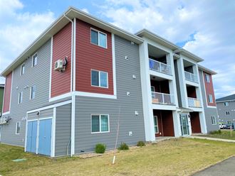 the exterior of an apartment building with gray and red siding