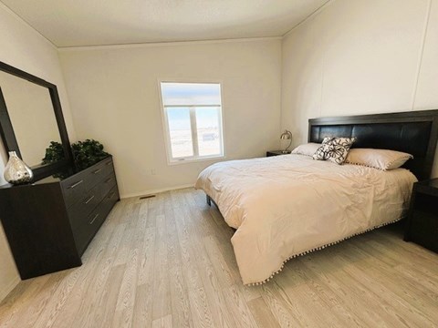 A bedroom with a bed, nightstand, and a mirror.