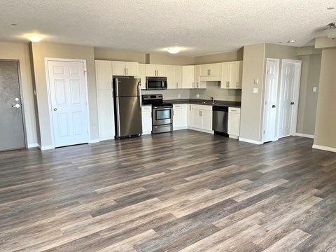 an open kitchen and living room with a wooden floor