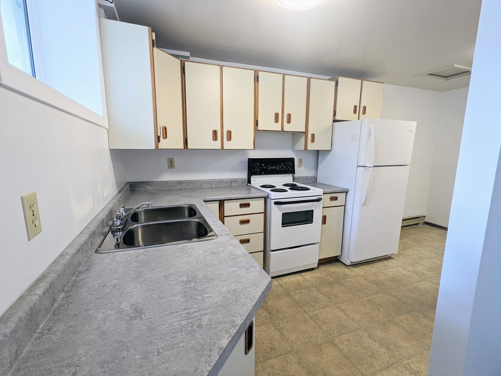 an empty kitchen with white appliances and white cabinets