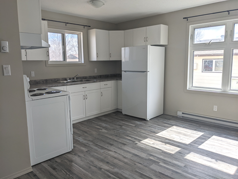 an empty kitchen with white appliances and white cabinets