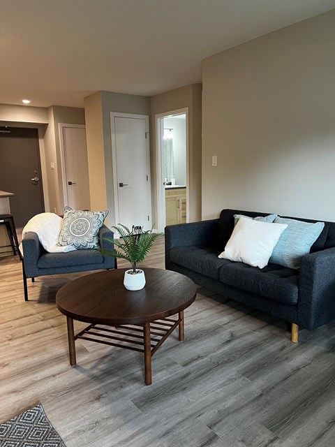 A living room with a black couch, a white chair, and a wooden coffee table.