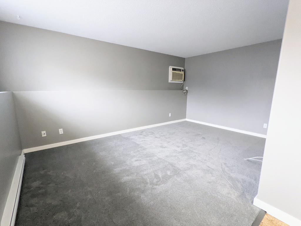 an empty living room with gray walls and a gray carpet
