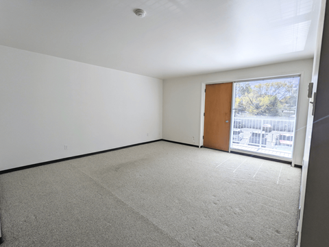 an empty living room with a door to a balcony