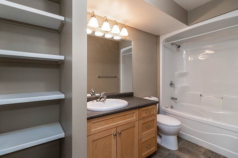 A bathroom with a sink, mirror, toilet and bathtub.