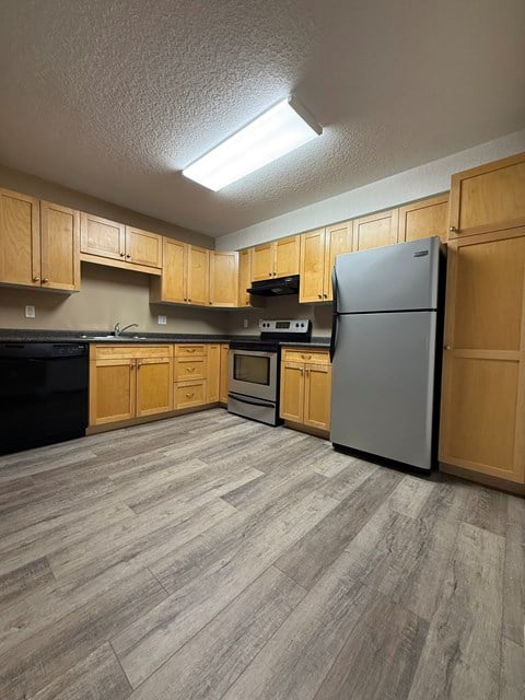 A kitchen with wooden cabinets and a grey refrigerator.