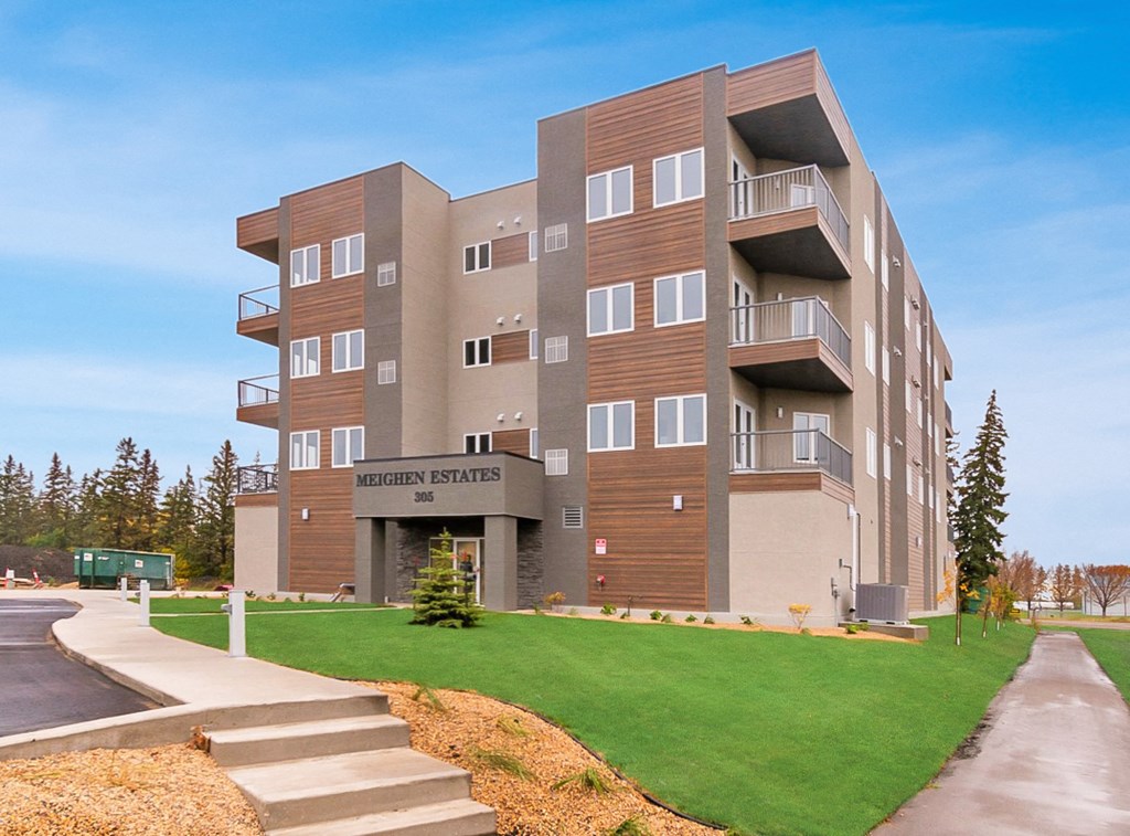an apartment building with a green lawn and steps in front of it