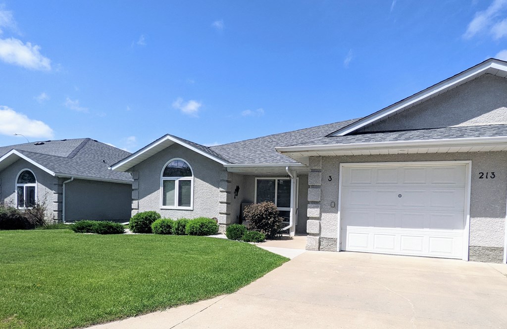 a gray house with a white garage door and a lawn