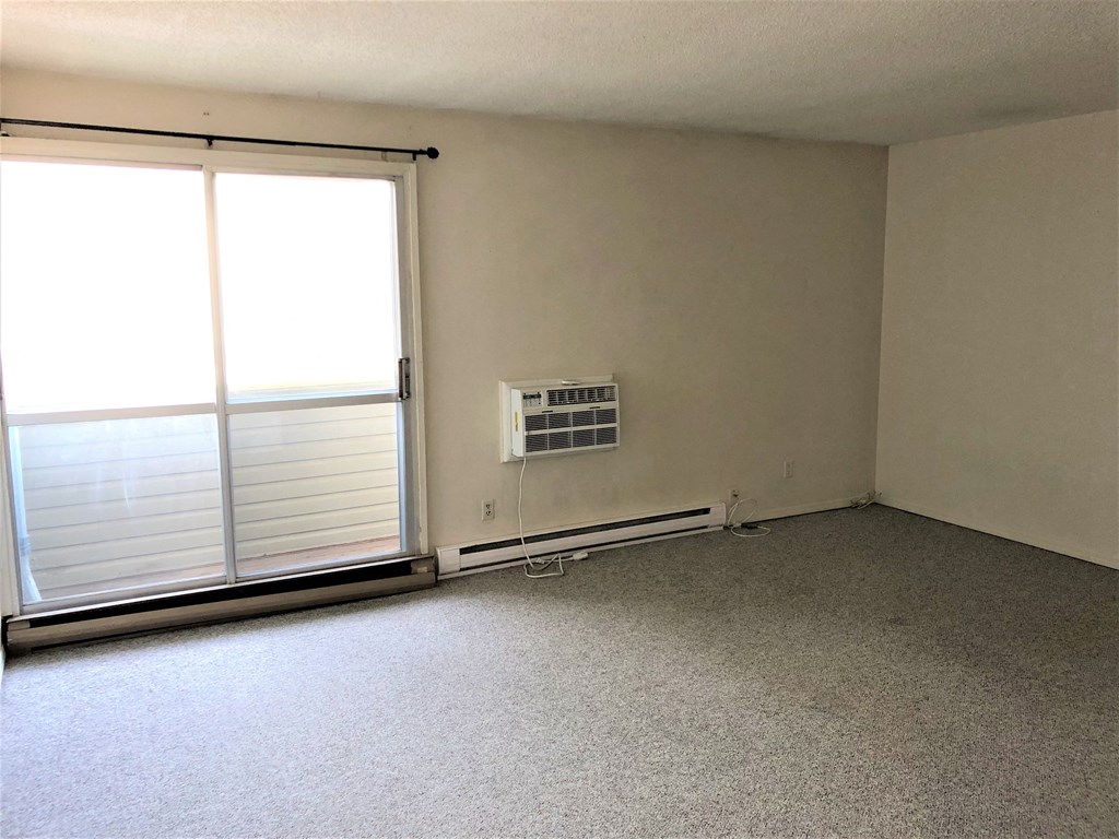 an empty room with a window and a air conditioner