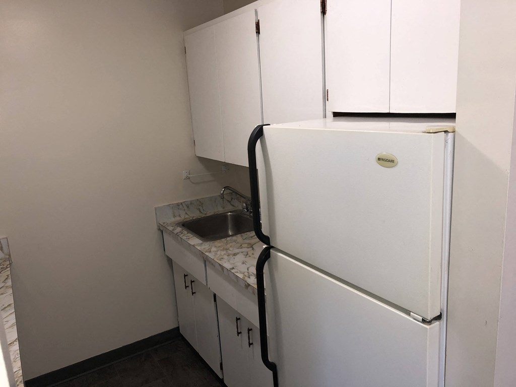 a kitchen with white cabinets and a refrigerator and a sink